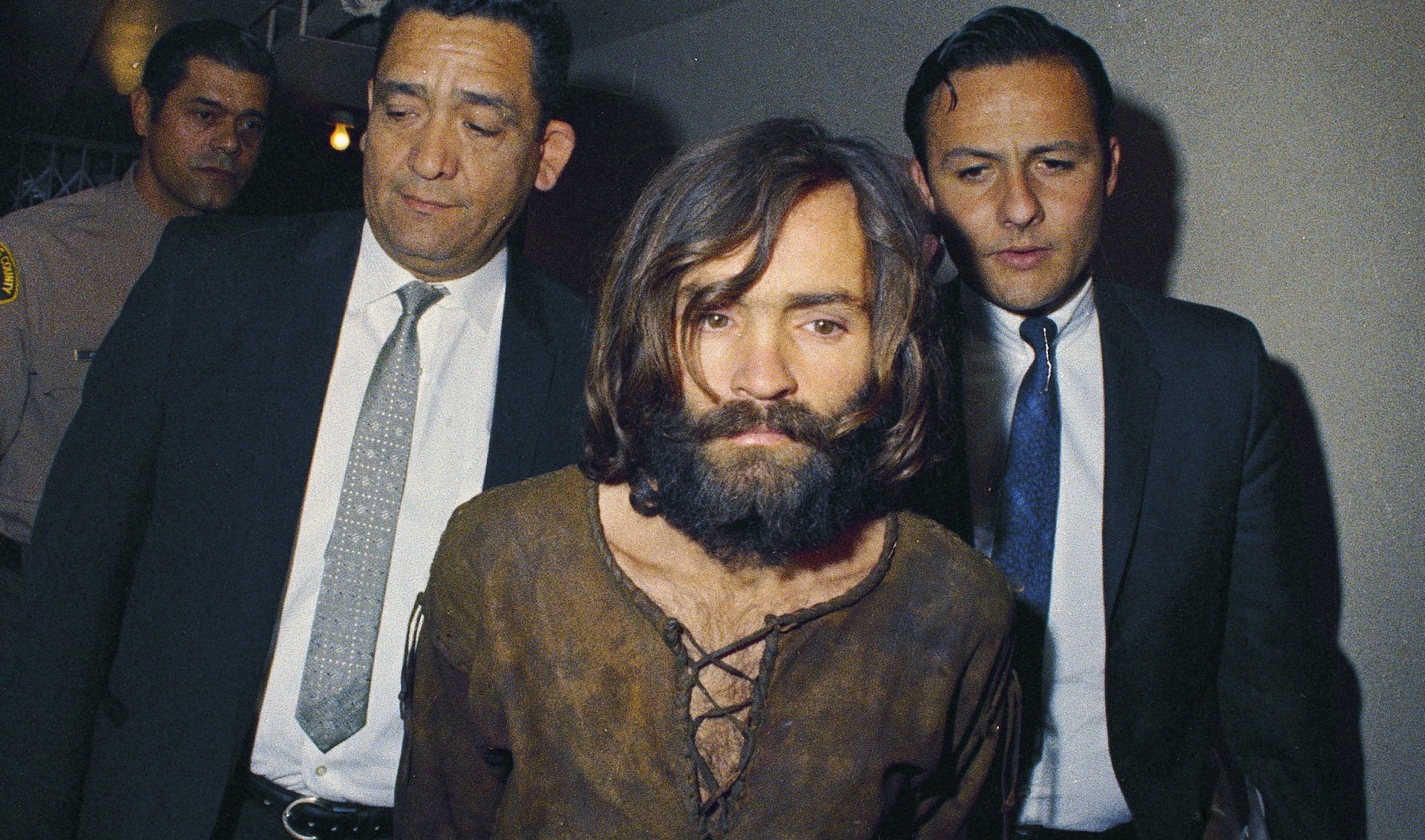 En esta foto de archivo de 1969, Charles Manson es acompañado a su acusación formal por cargos de conspiración y asesinato en relación con el caso de Sharon Tate (AP Photo, File)