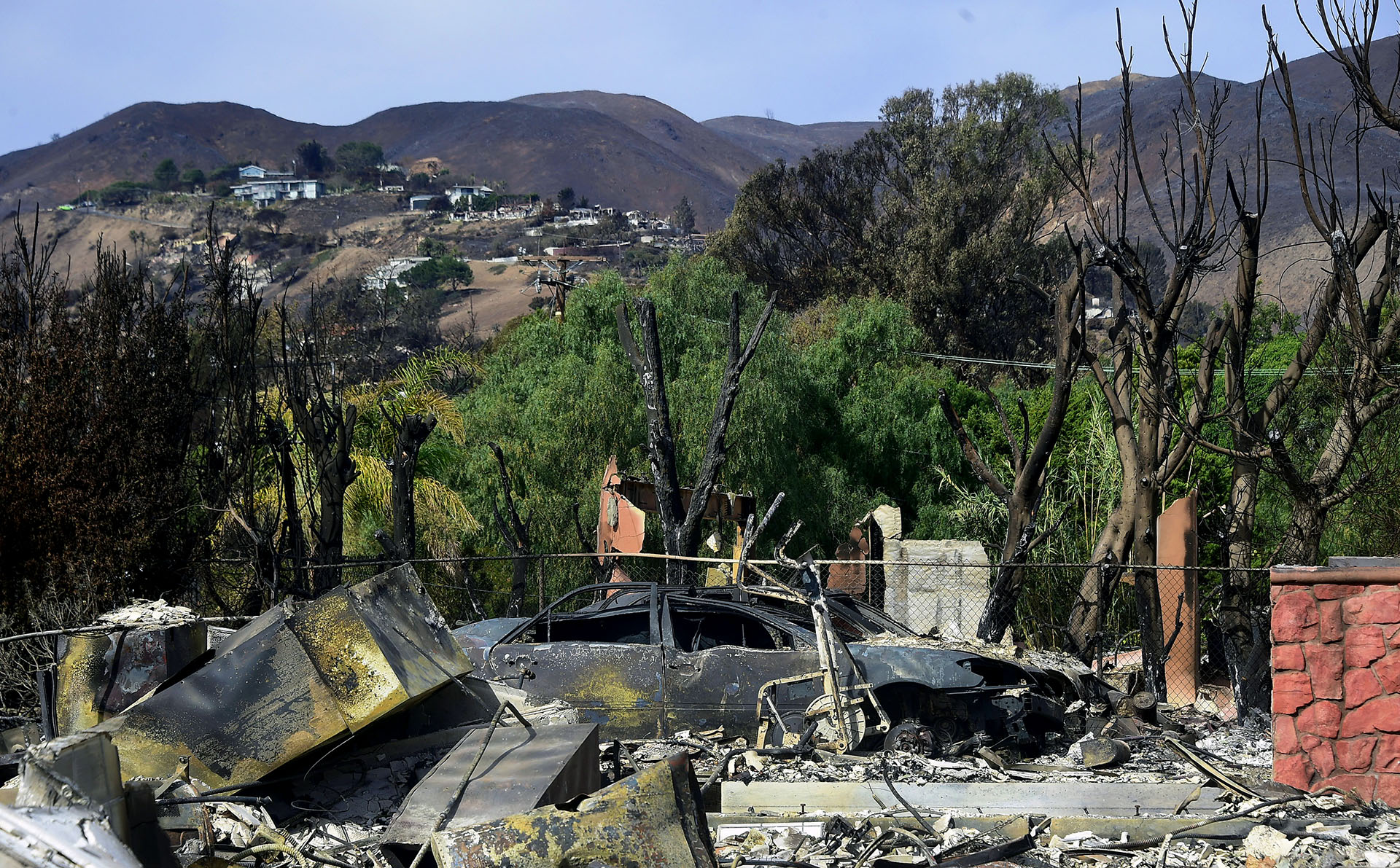 De fondo, algunas casas se ven a salvo, mientras que otras, en primer plano, fueron arrasadas por las llamas