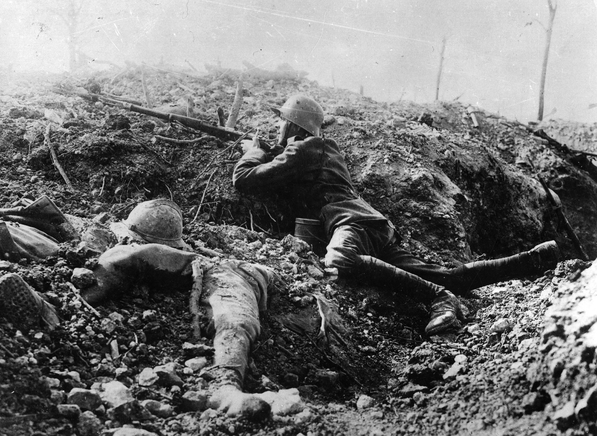 Un soldado alemán agazapado en los cráteres dejados por las bombas y junto al cadáver de un francés (Getty)