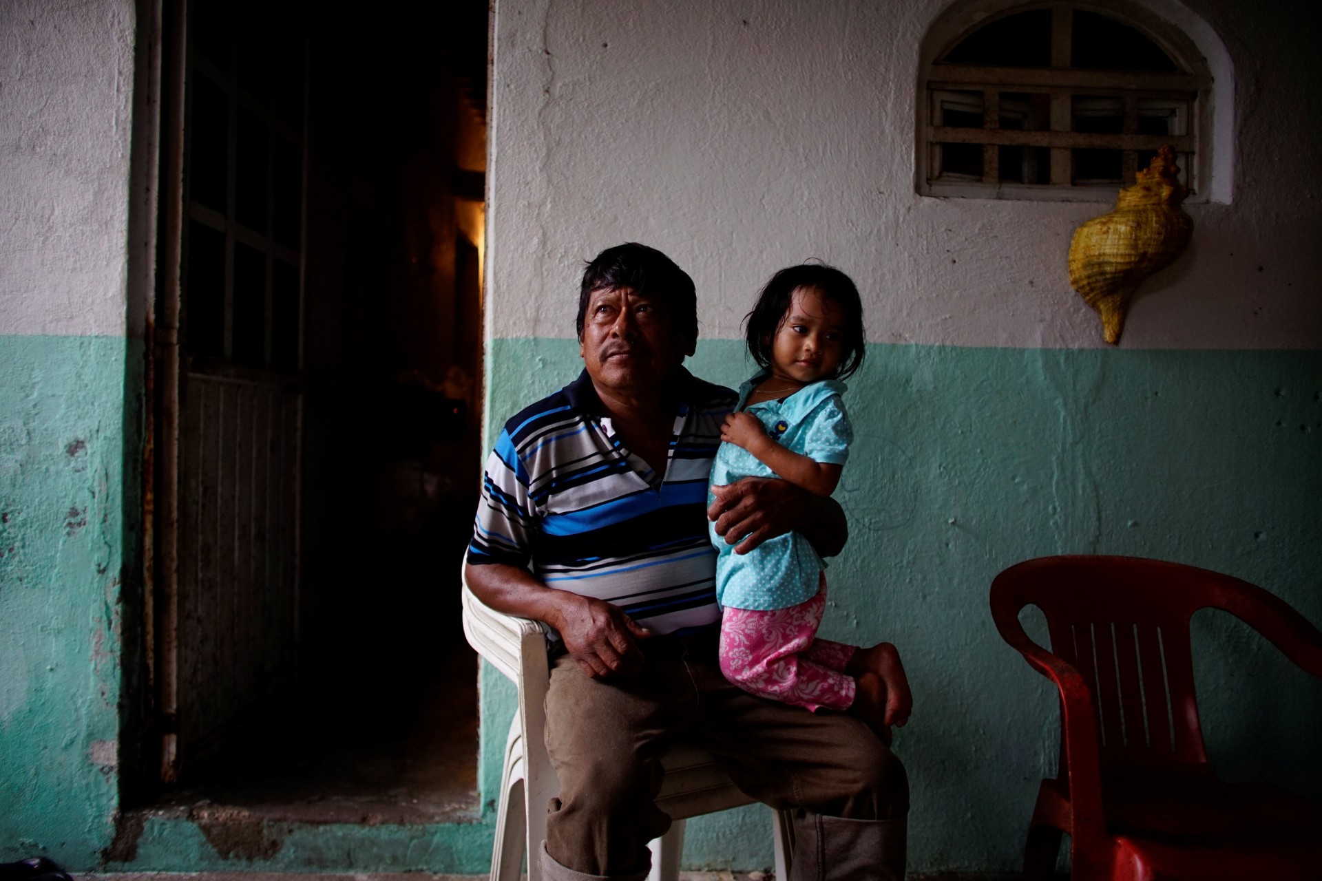El pescador Rafael de la Cruz Hernández, de 60 años, tiene a su nieta de dos años en el pueblo de Chiltepec, en Paraiso, México, el 9 de diciembre de 2018.