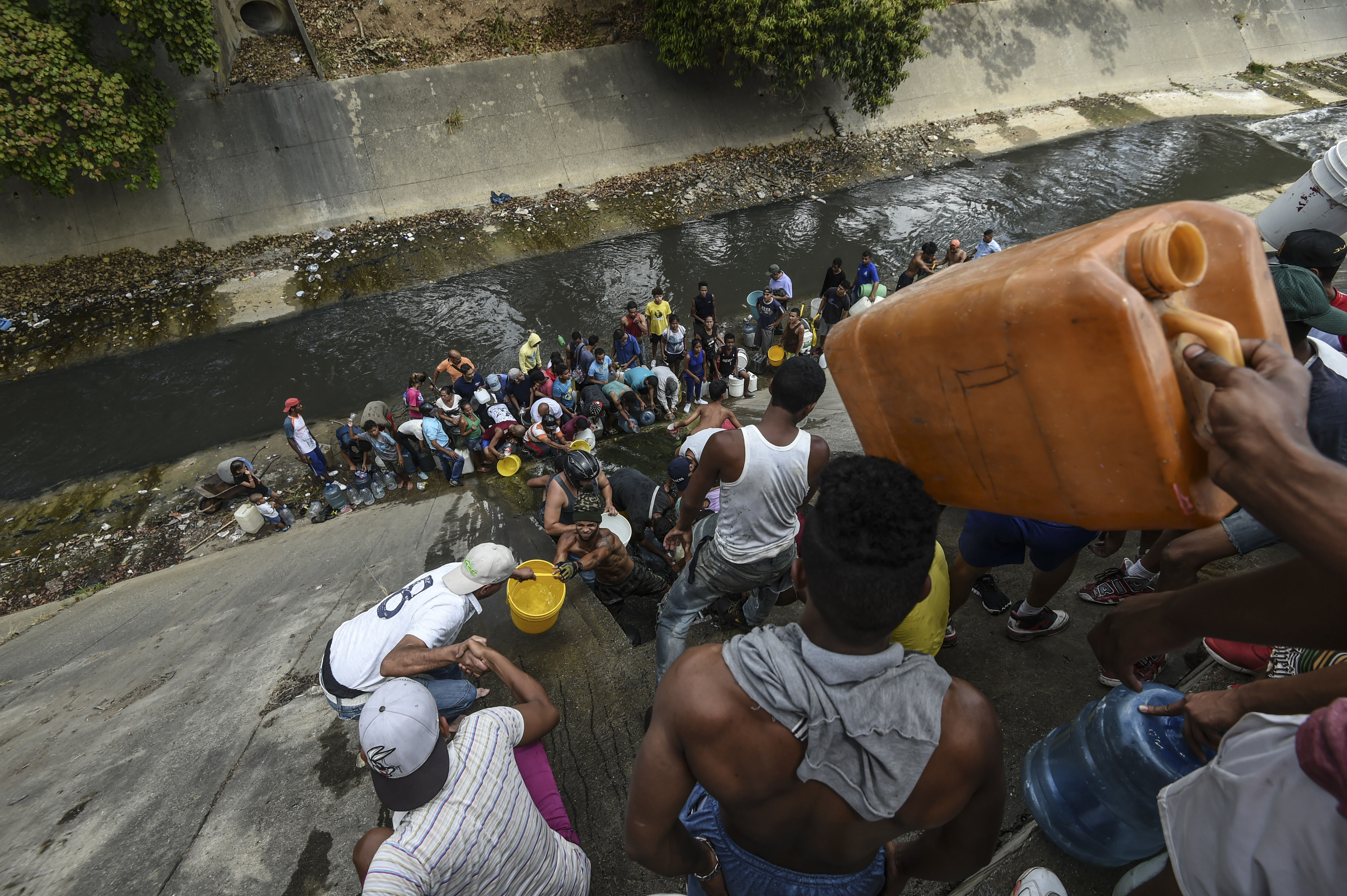 Decenas de personas buscan agua del río Guaire (Photo by JUAN BARRETO / AFP)